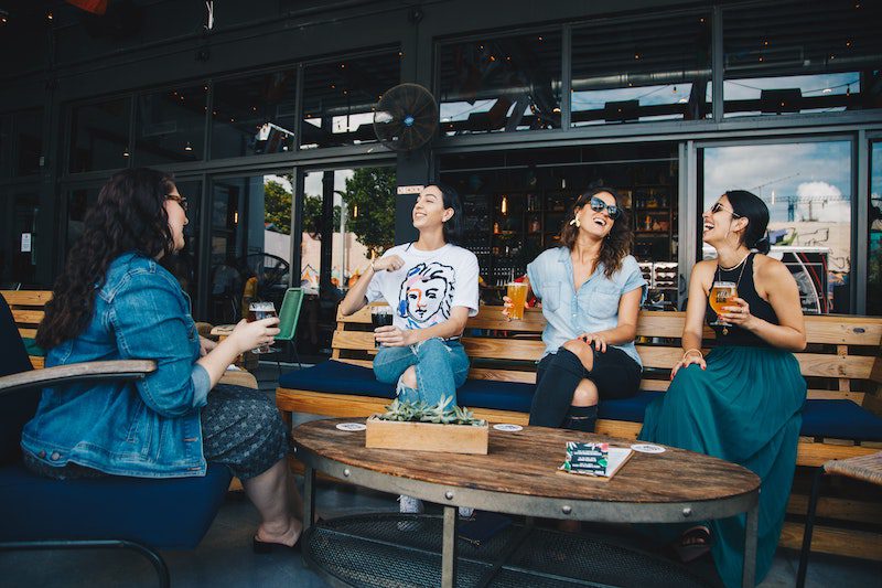 women sitting together - how to get a date with a girl when she's with a group of friends